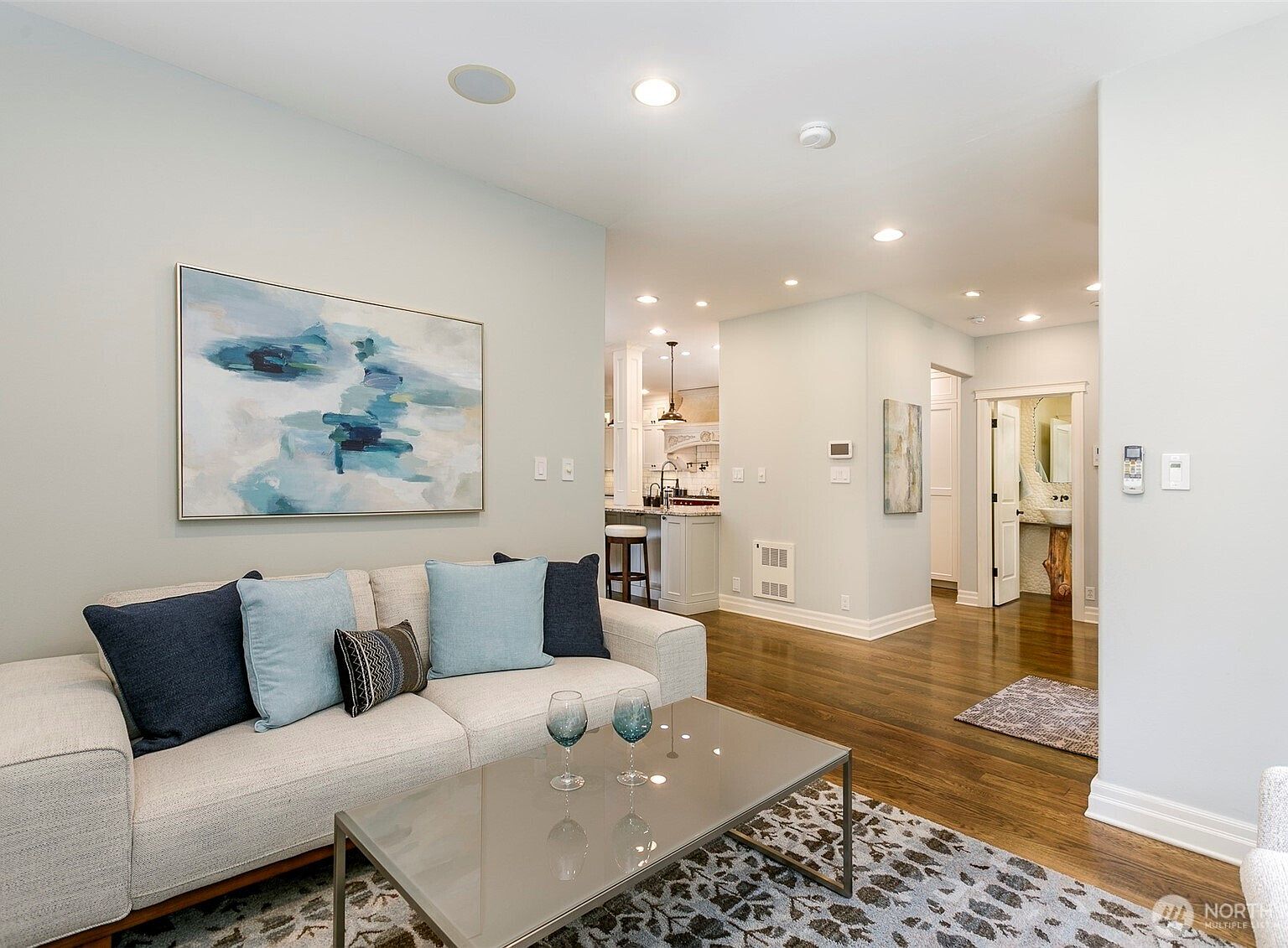 Formal living room with a large abstract canvas on a pale wall, a low pale sofa, and an open sightline through to the kitchen and back of the house